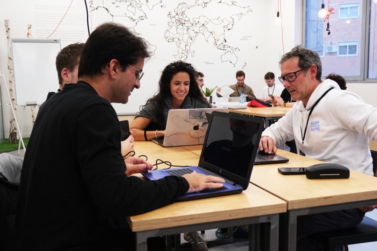 Participantes del hackatón del NoCode Day trabajando con sus portátiles en una mesa compartida.